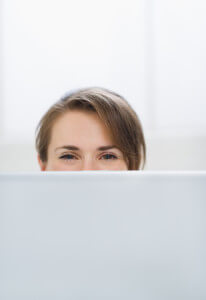 Woman hiding behind laptop screen